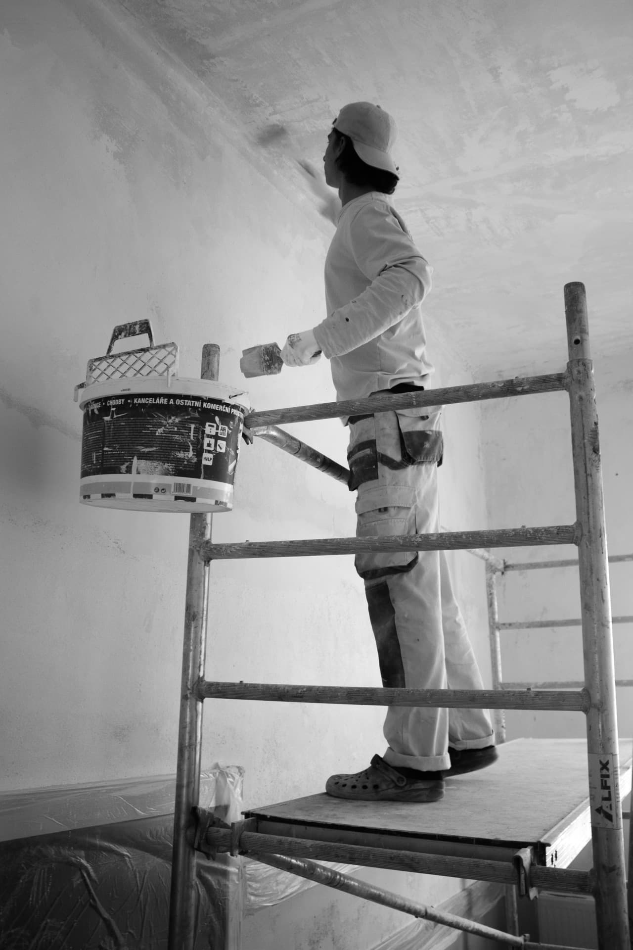 Decorator painting a ceiling on scaffolding