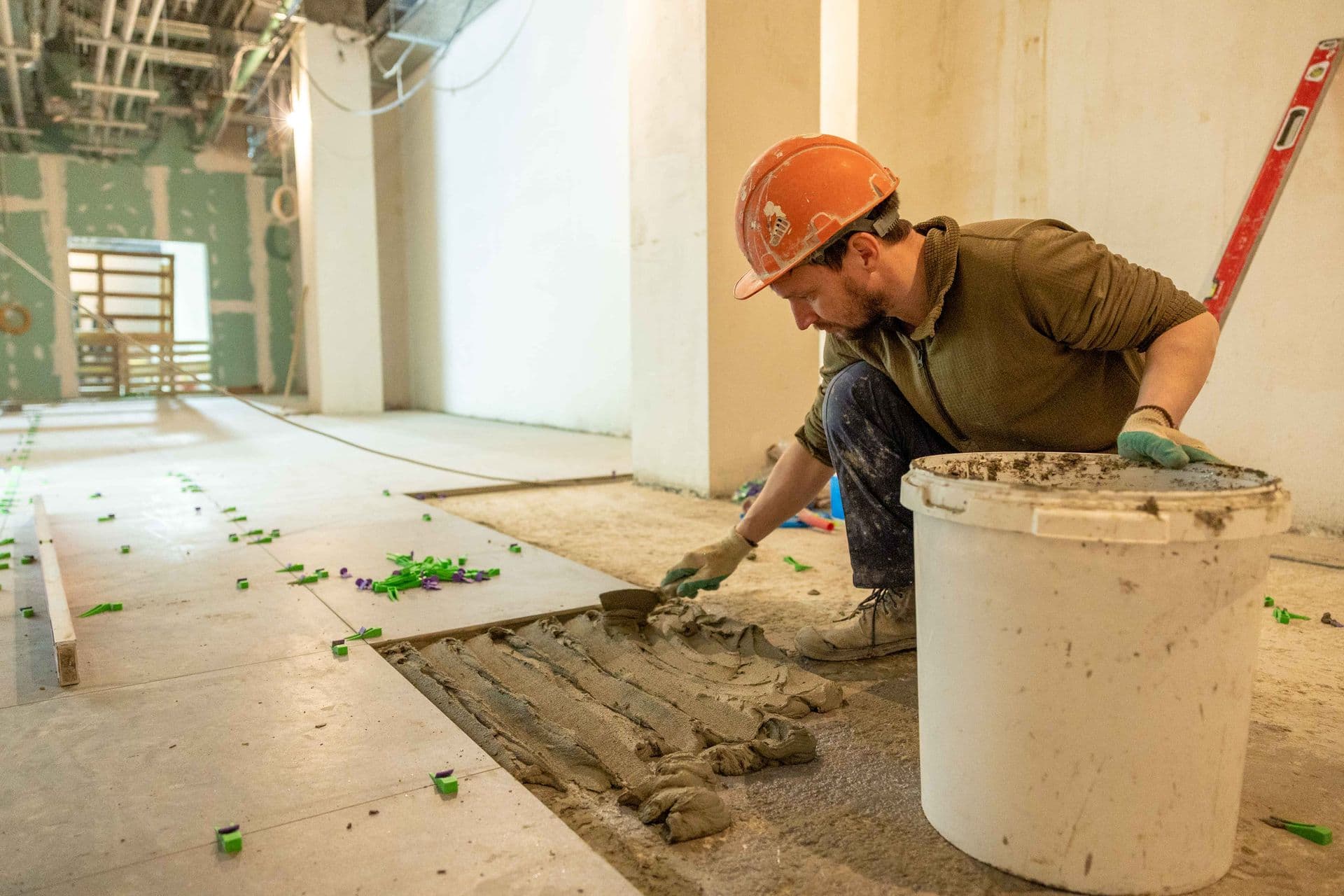 Worker laying floor tiles during a renovation
